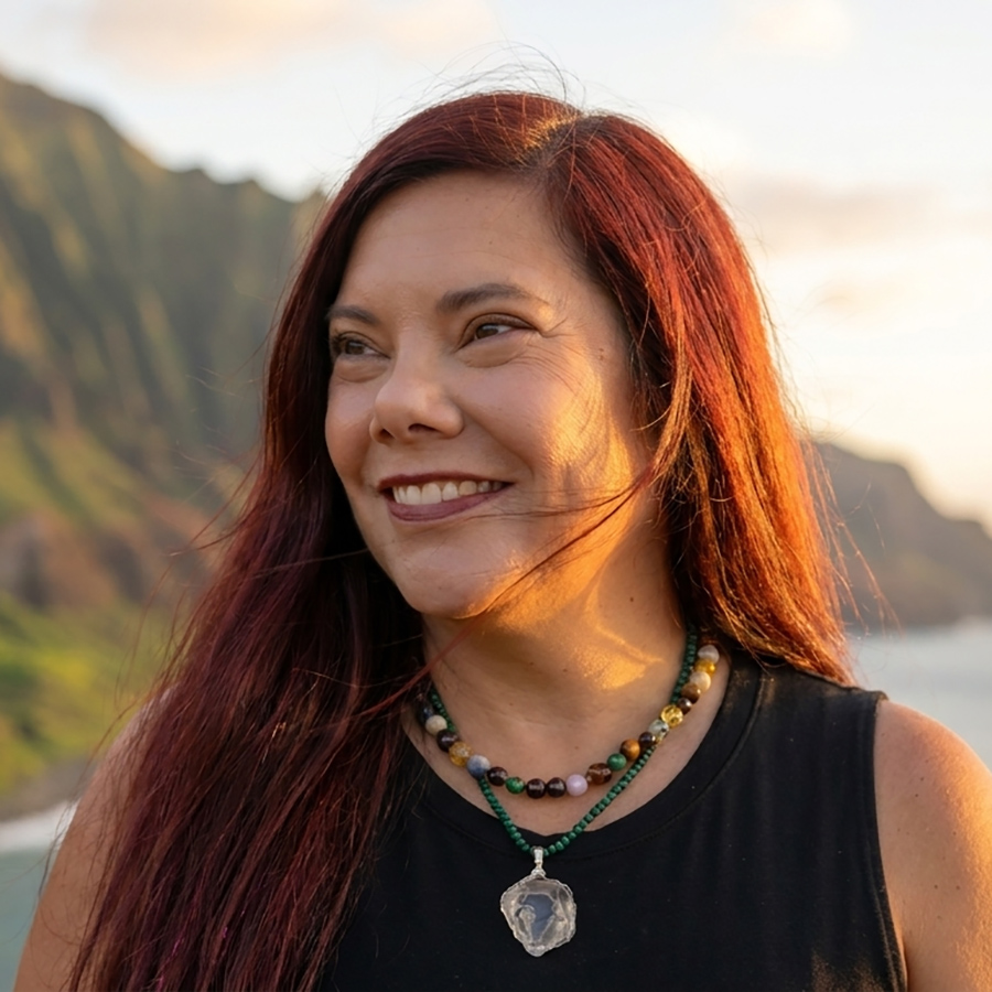Smiling red-haired woman near a mountain coastline at golden hour.